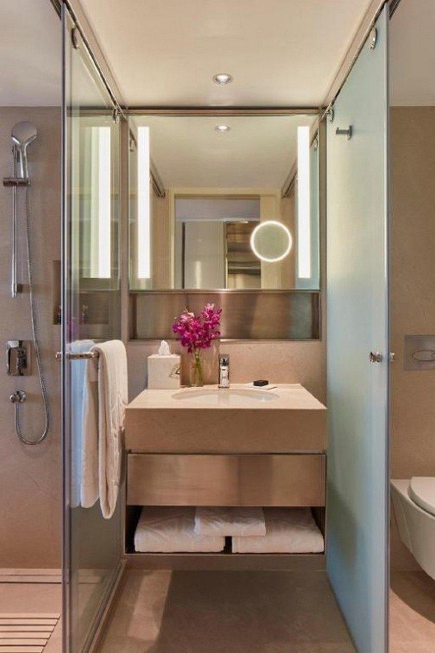 The Taj Mahal Tower, Mumbai Hotel Kültér fotó The photo shows a modern bathroom. It features a sleek, minimalistic design with a light-colored sink unit that includes a smooth countertop. On the countertop, there is a vase with purple flowers and a few toiletries. A large mirror with integrated 