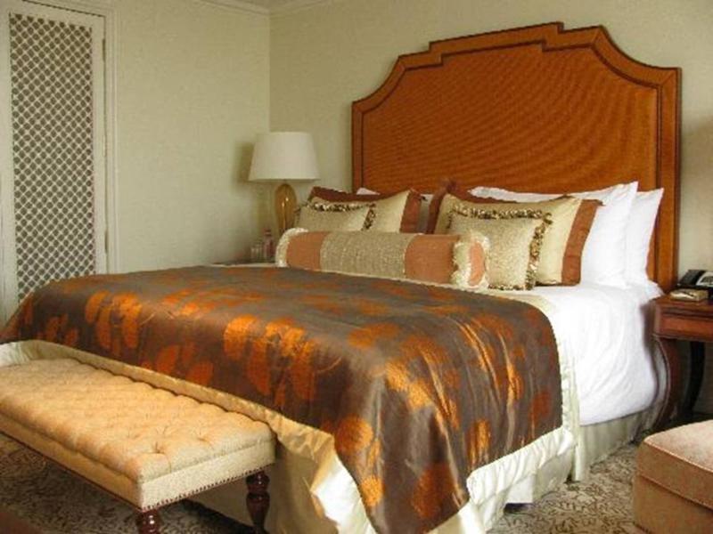 The Taj Mahal Tower, Mumbai Hotel Kültér fotó The photo shows a well-decorated bedroom featuring a large bed with an ornate headboard. The bed is dressed with a luxurious comforter that has a blend of rich colors, including brown and gold accents, along with multiple decorative pillows. At the f
