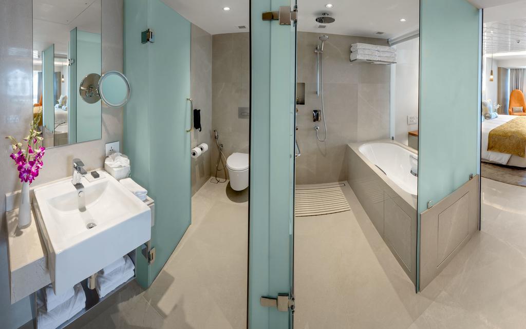 The Taj Mahal Tower, Mumbai Hotel Kültér fotó The photo shows a modern bathroom with a sleek design. To the left, there is a sink with a mirror above it, and beneath the sink, there are some storage shelves. The area also features a glass partition leading to a shower. On the right side, there i