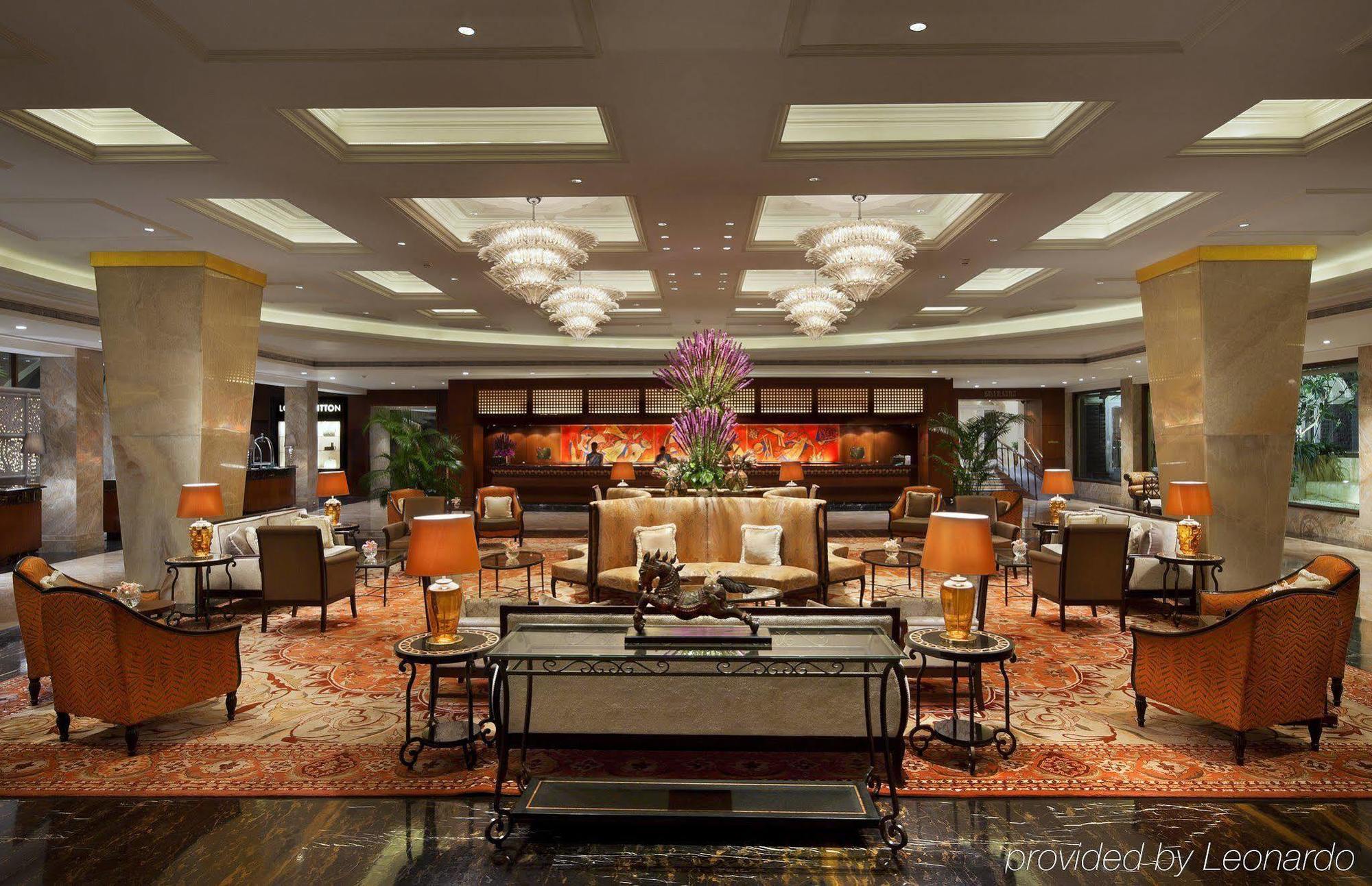 The Taj Mahal Tower, Mumbai Hotel Kültér fotó The photo shows an elegant hotel lobby. It features a spacious area with plush seating, including stylish armchairs and sofas arranged around coffee tables. Central to the space is a large flower arrangement, adding a touch of color and sophisticatio