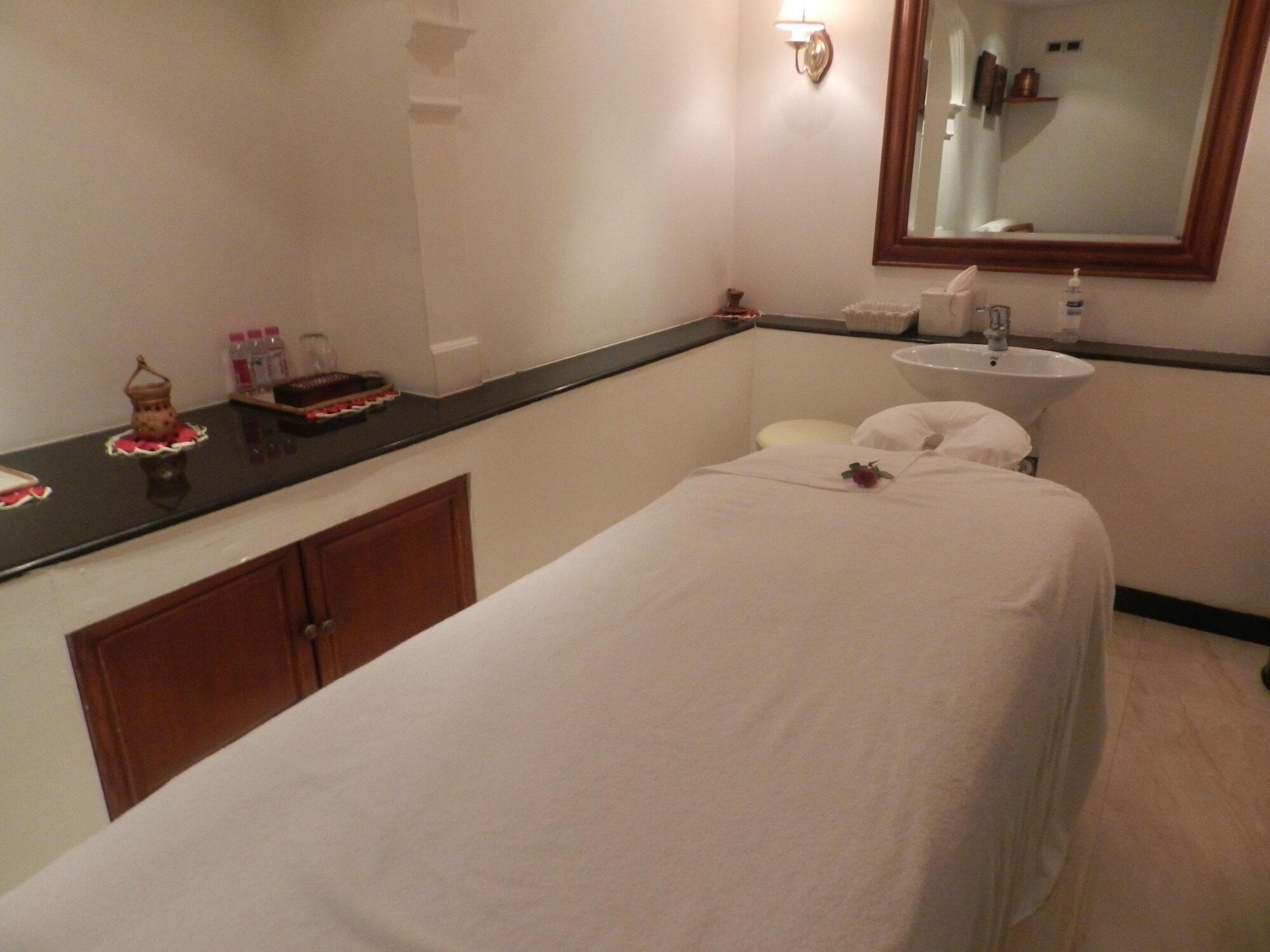 The Taj Mahal Tower, Mumbai Hotel Kültér fotó The photo shows a serene spa room designed for relaxation and treatments. In the center, there is a massage table covered with a white sheet. There is a small decorative item, possibly a flower, placed on the table. Alongside, a dark countertop displ